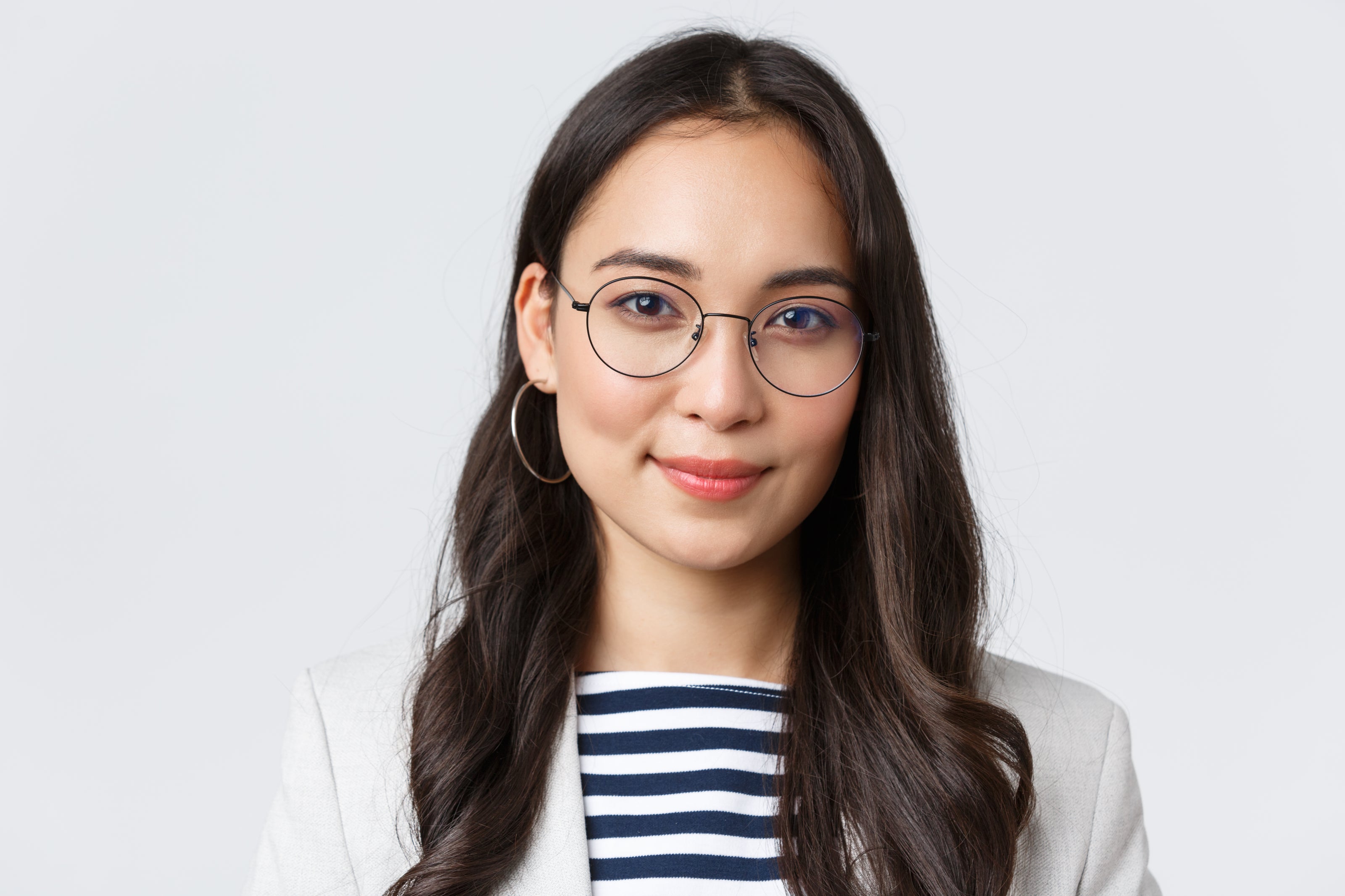 Woman wearing glasses and a striped shirt against a plain background