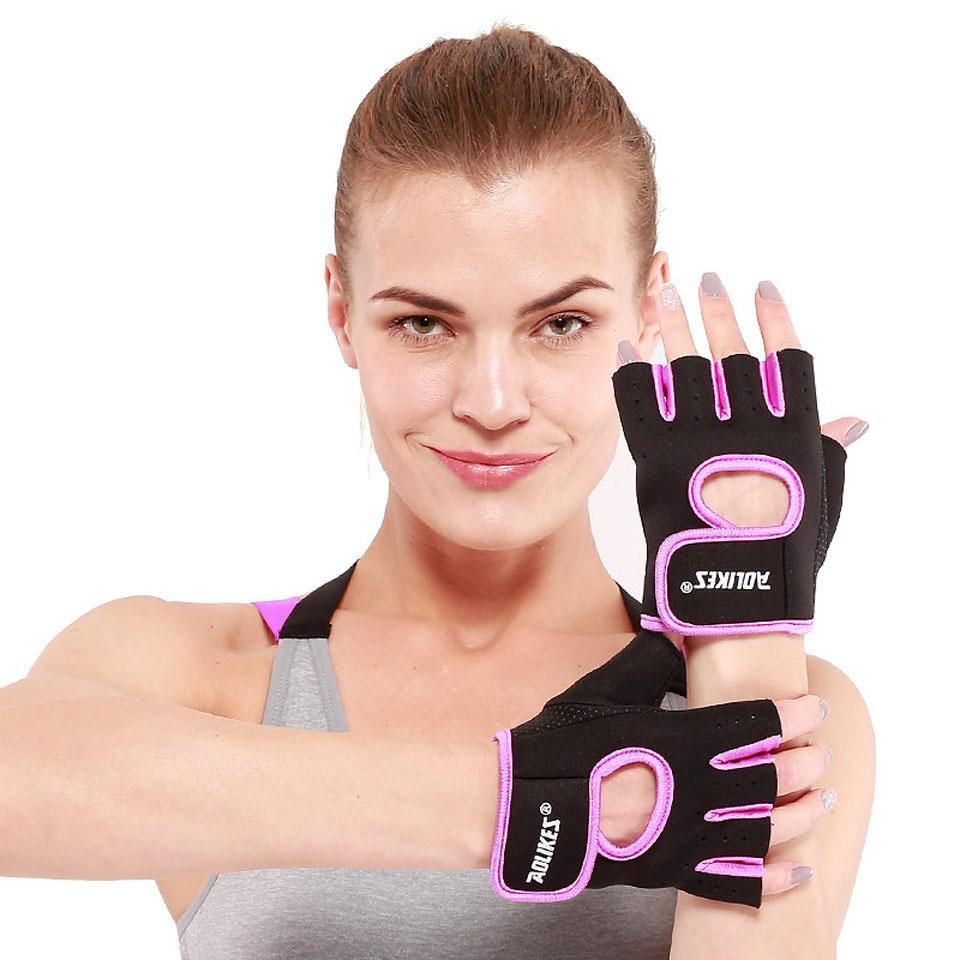 Woman wearing black and pink fitness gloves with visible branding on a white background