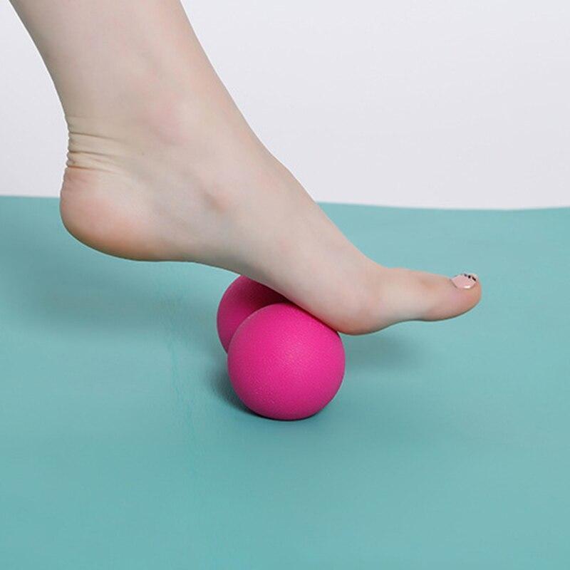 Person using a pink massage ball on their foot against a light blue background