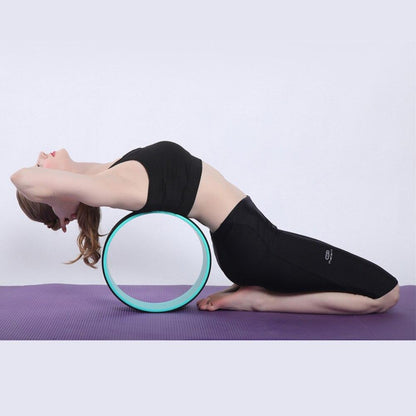 Person using a yoga wheel on a purple mat with a white background