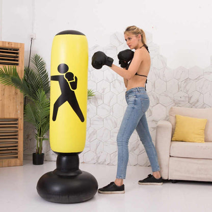 Woman practicing boxing on a yellow punching bag in a living room.