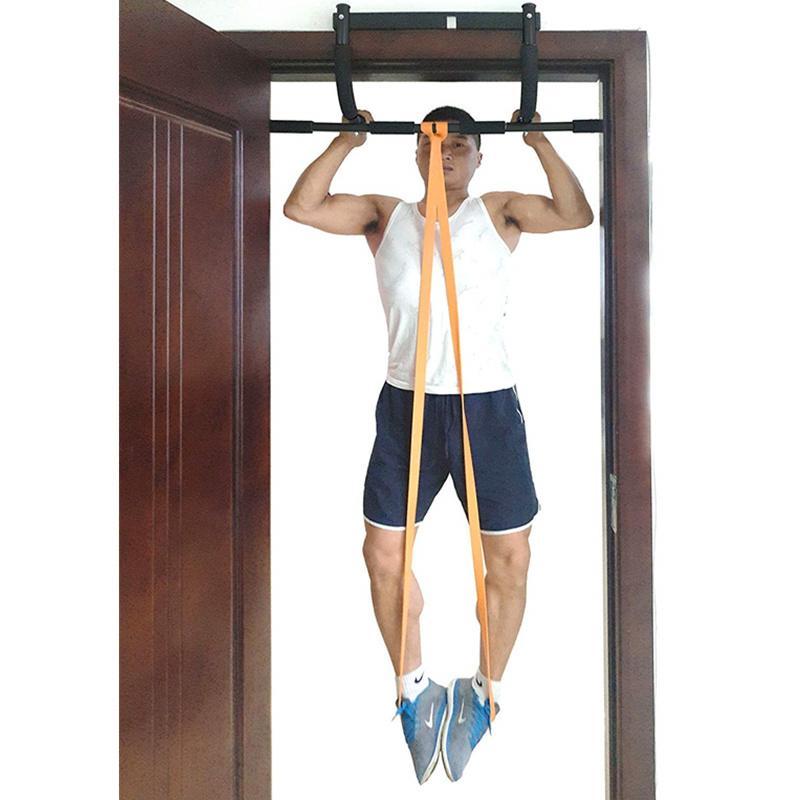 Person using a pull-up bar with resistance bands inside a room.