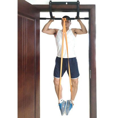 Person using a pull-up bar with resistance bands inside a room.