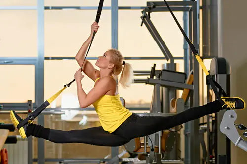 Woman exercising with TRX suspension straps in a gym setting