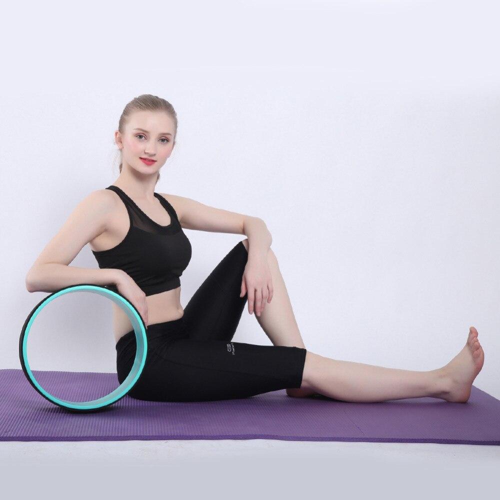 Woman using a yoga wheel on a purple mat with a white background