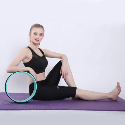Woman using a yoga wheel on a purple mat with a white background