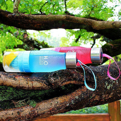 Colorful water bottle with a straw on a tree branch outdoors