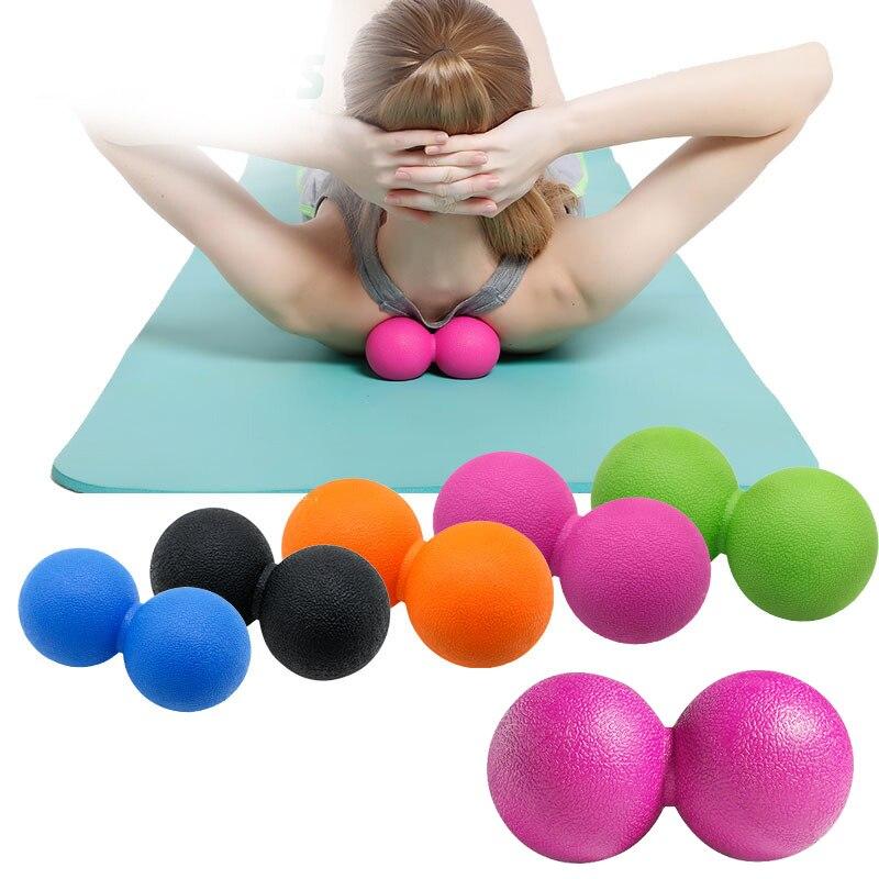 Person using a pink massage ball on a yoga mat with additional colorful massage balls displayed below.