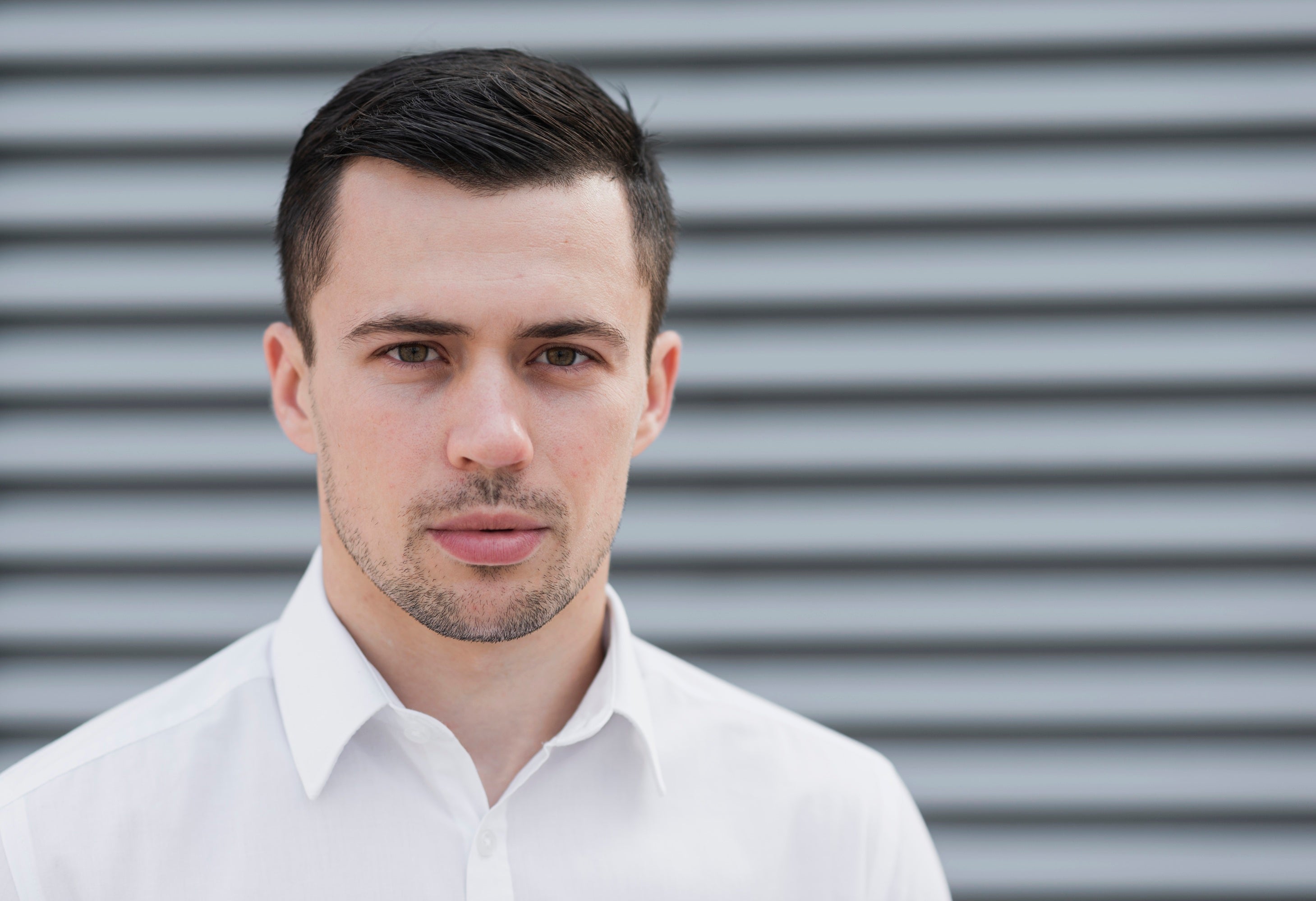 Man wearing a white shirt against a metallic shutter background